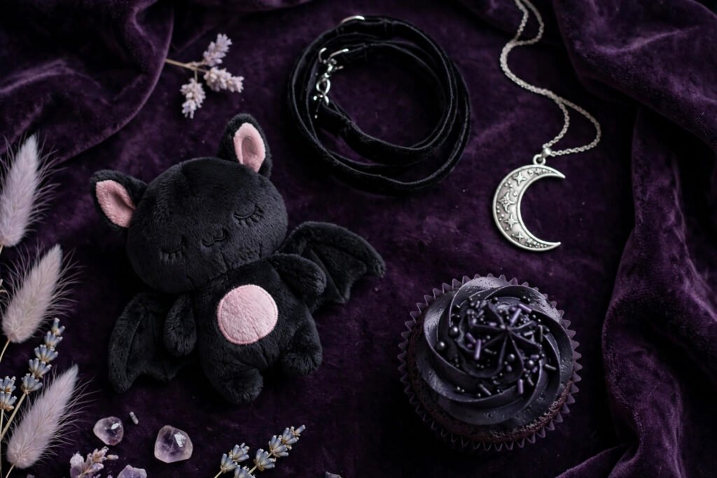 Cute pastel goth flat lay with bat plush and moon jewelry on velvet